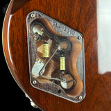 Close-up of a guitar's control plate showing the internal wiring, dual potentiometers, and two yellow electrolytic capacitors labeled 470UF 25V on a glossy brown wood body.