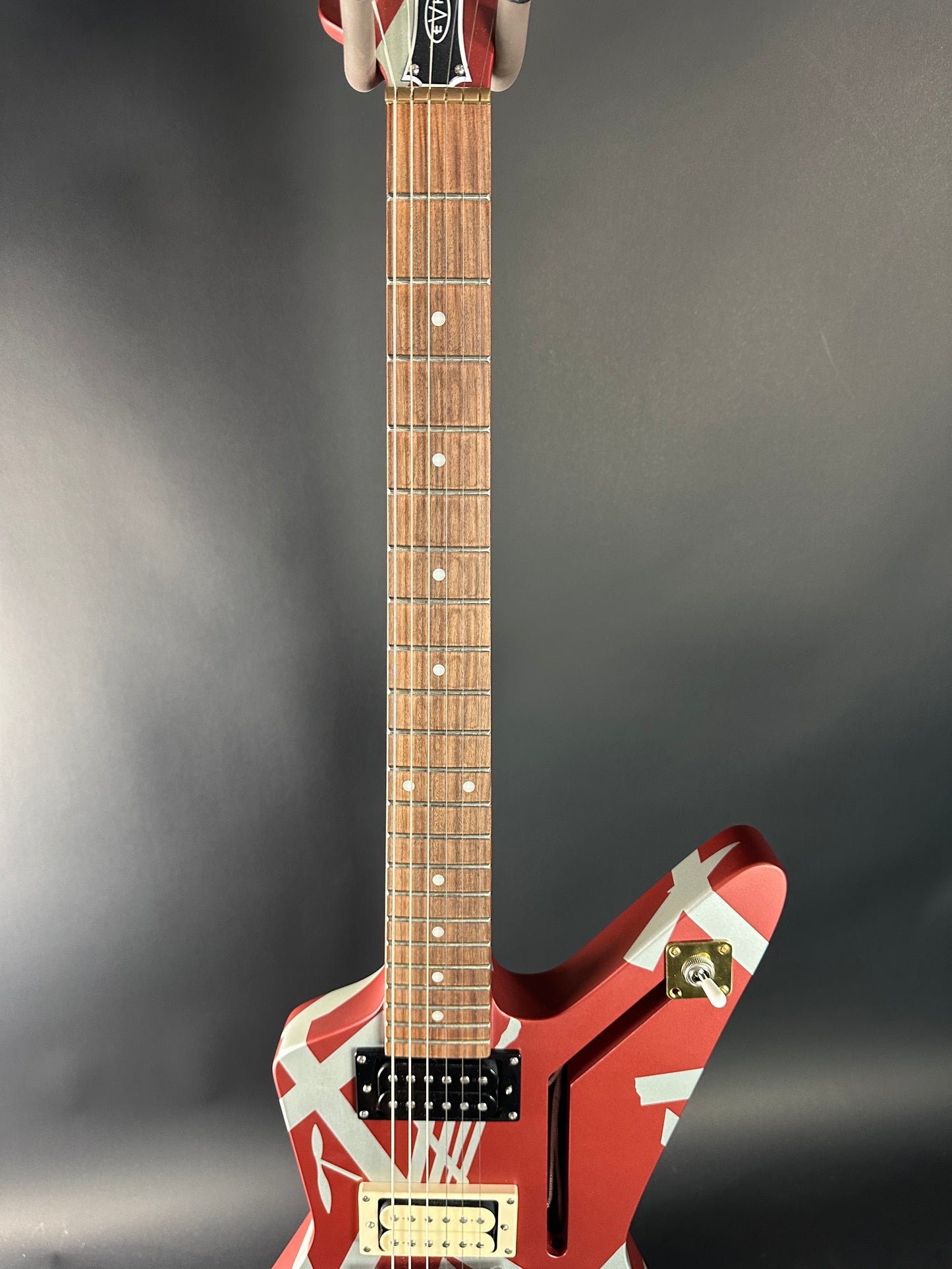 Red electric guitar with white stripes on a dark gray background