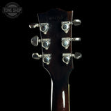 Close-up of a guitar headstock with six silver tuning pegs on a black background. A Tone Shop watermark is visible in the top left corner.