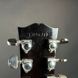 Close-up of the headstock of a vintage guitar, showing four silver tuning pegs with 'GROVER' branding and the serial number '13156715' engraved on the dark wood backplate against a gray background.