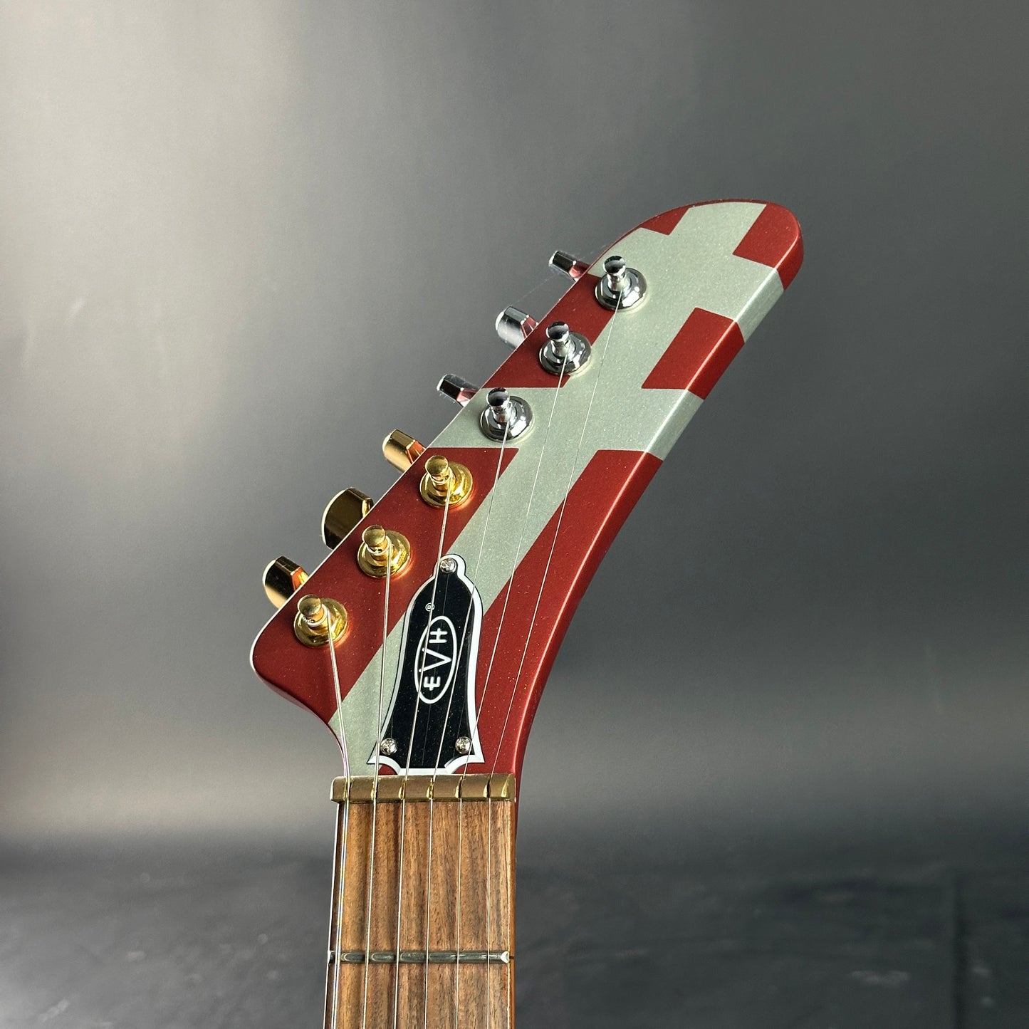 Guitar headstock with red and white design on a gray background