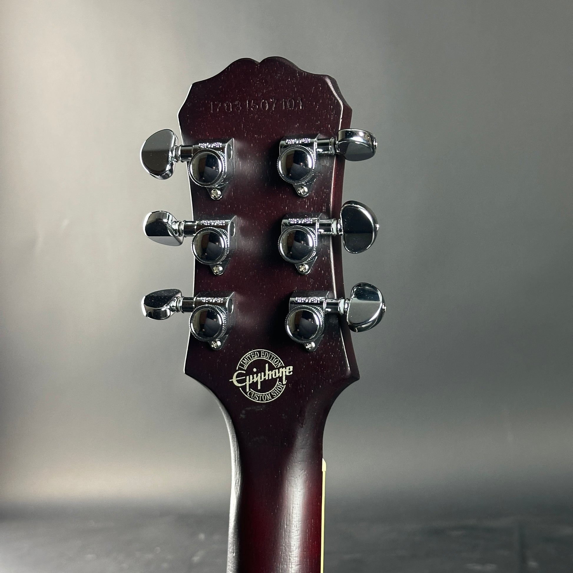 Guitar headstock with Epiphone logo on a gray background