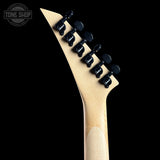 Close-up of the headstock of an electric guitar with a light natural wood finish and six black tuning pegs, shown against a solid black background. A Tone Shop watermark is visible in the top-left corner.