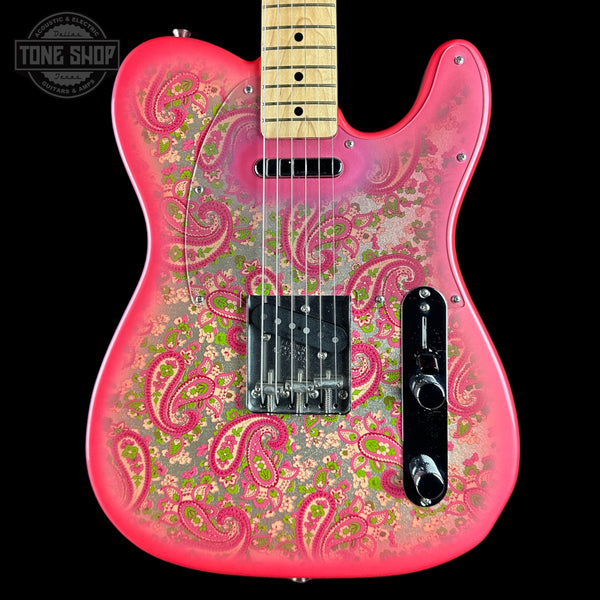 A pink electric guitar with a vibrant paisley and floral pattern in pink, green, and gold over a glossy finish, shown against a solid black background with a Tone Shop watermark in the top left corner.