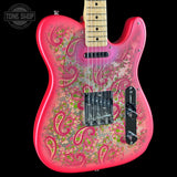 A custom electric guitar with a vibrant pink body featuring a detailed paisley and floral pattern in green, gold, and pink over a metallic silver base. The neck is a natural maple wood color, and the headstock is partially visible at the top edge.