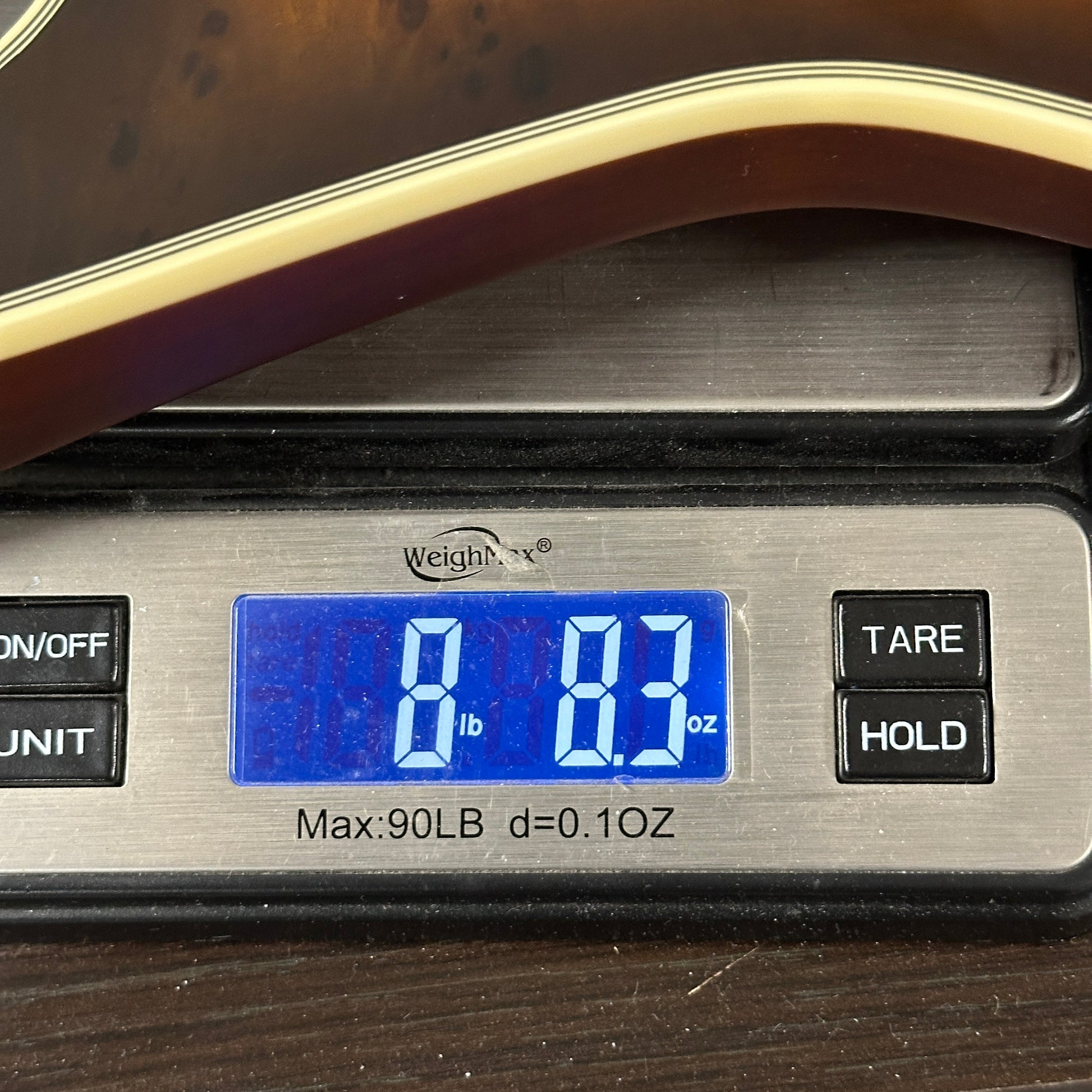 Digital scale displaying weight with a blue screen on a wooden surface