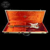 An electric guitar with a dark red body and white pickguard displayed inside an open hard case with a textured orange interior. The Tone Shop logo is visible in the top left corner.