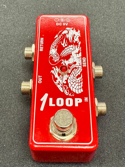 Red guitar effects pedal with dragon design on a gray surface