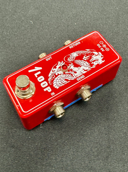 Red guitar effects pedal with dragon design on a gray surface