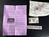 Analog Man King Of Transgression V4.0 Mar-09 package contents laid out on a black surface, including a purple instruction sheet, a white branded drawstring pouch, a sticker, a card, and a small black accessory.