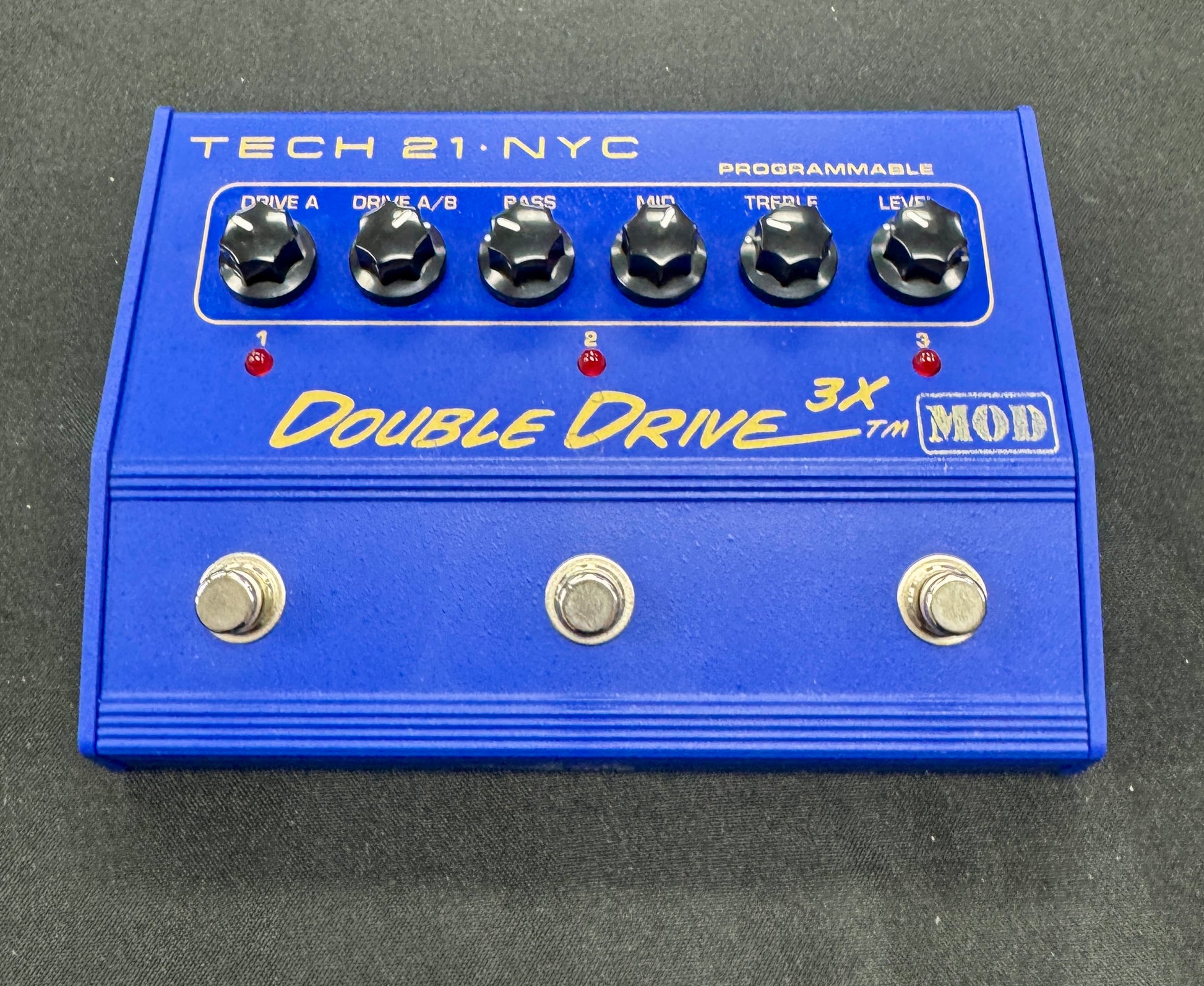 Blue guitar effects pedal with 'Tech 21 NYC' branding on a gray background