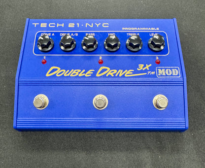 Blue guitar effects pedal with 'Tech 21 NYC' branding on a gray background