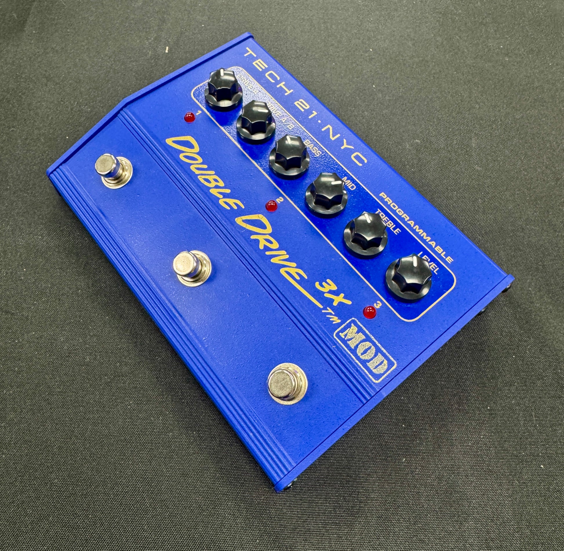Blue guitar effects pedal with 'Tech 21 NYC' branding on a dark surface