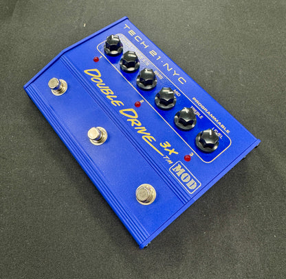Blue guitar effects pedal with 'Tech 21 NYC' branding on a dark surface