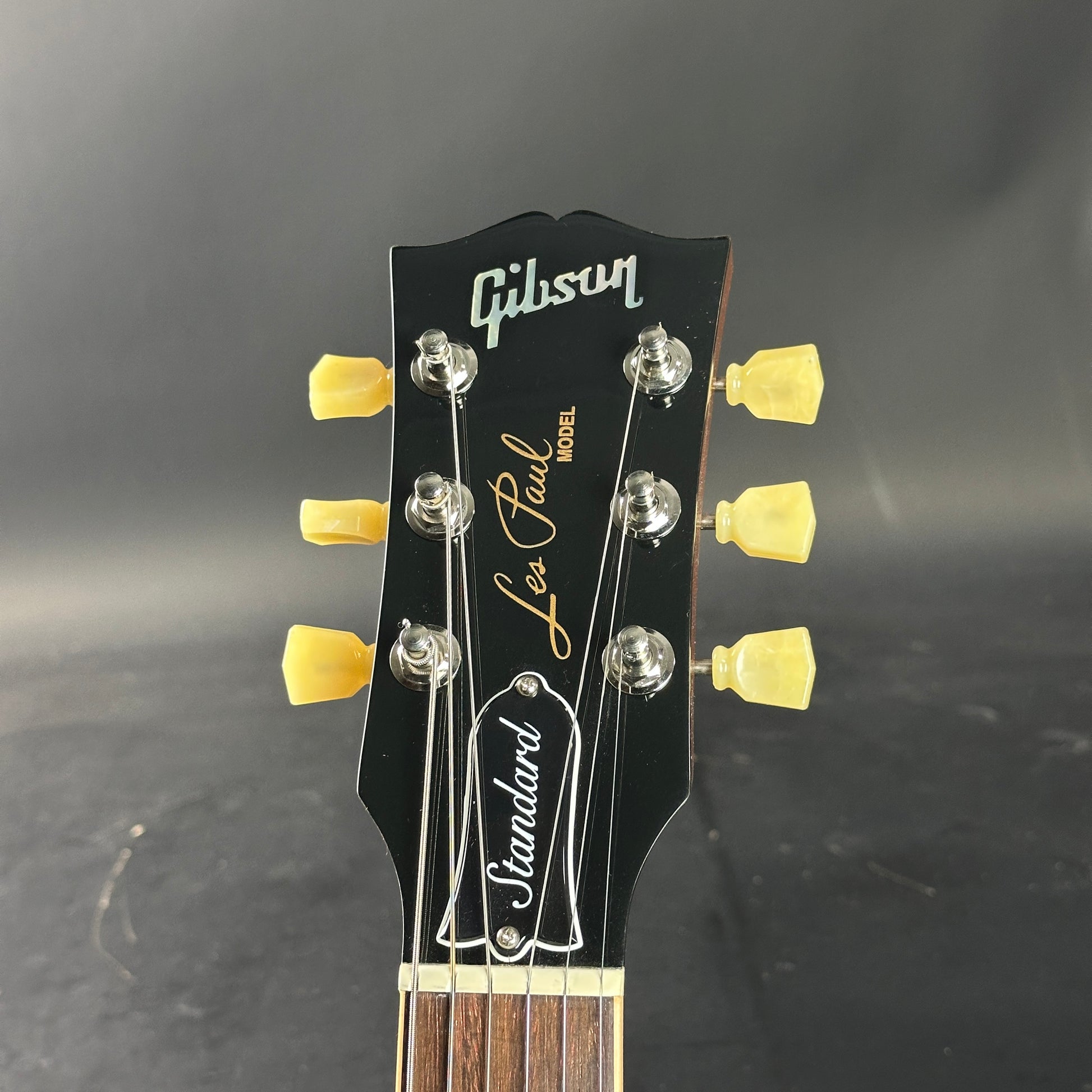 Gibson Les Paul guitar headstock with yellow tuning pegs on a dark background