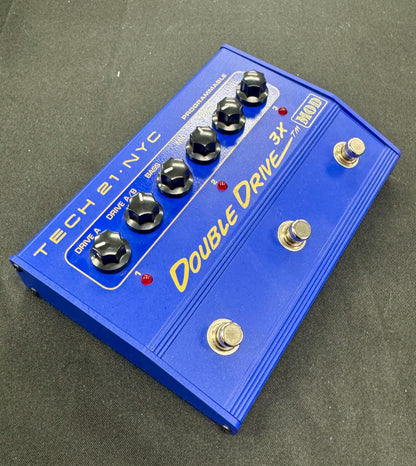 Blue guitar effects pedal with 'Double Drive 3x' on a gray background