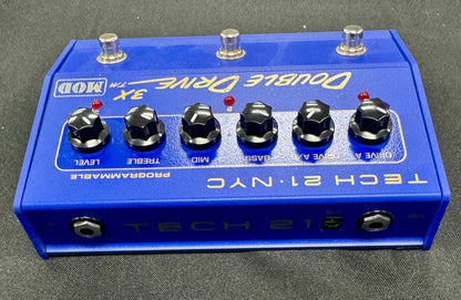 Blue guitar effects pedal with knobs and labels on a gray background