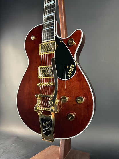 Close-up of a brown electric guitar with gold hardware on a gray background