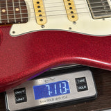 A close-up of a red glitter electric guitar body resting on a digital scale displaying 7.13 lbs.