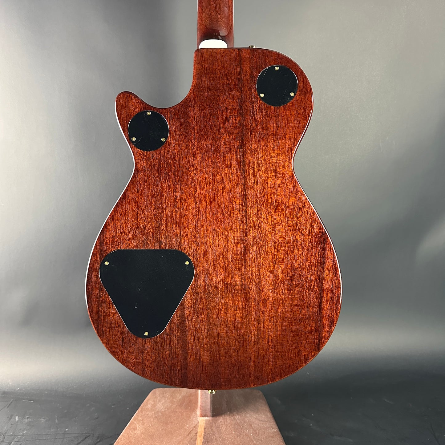 Back view of a wooden electric guitar on a gray background