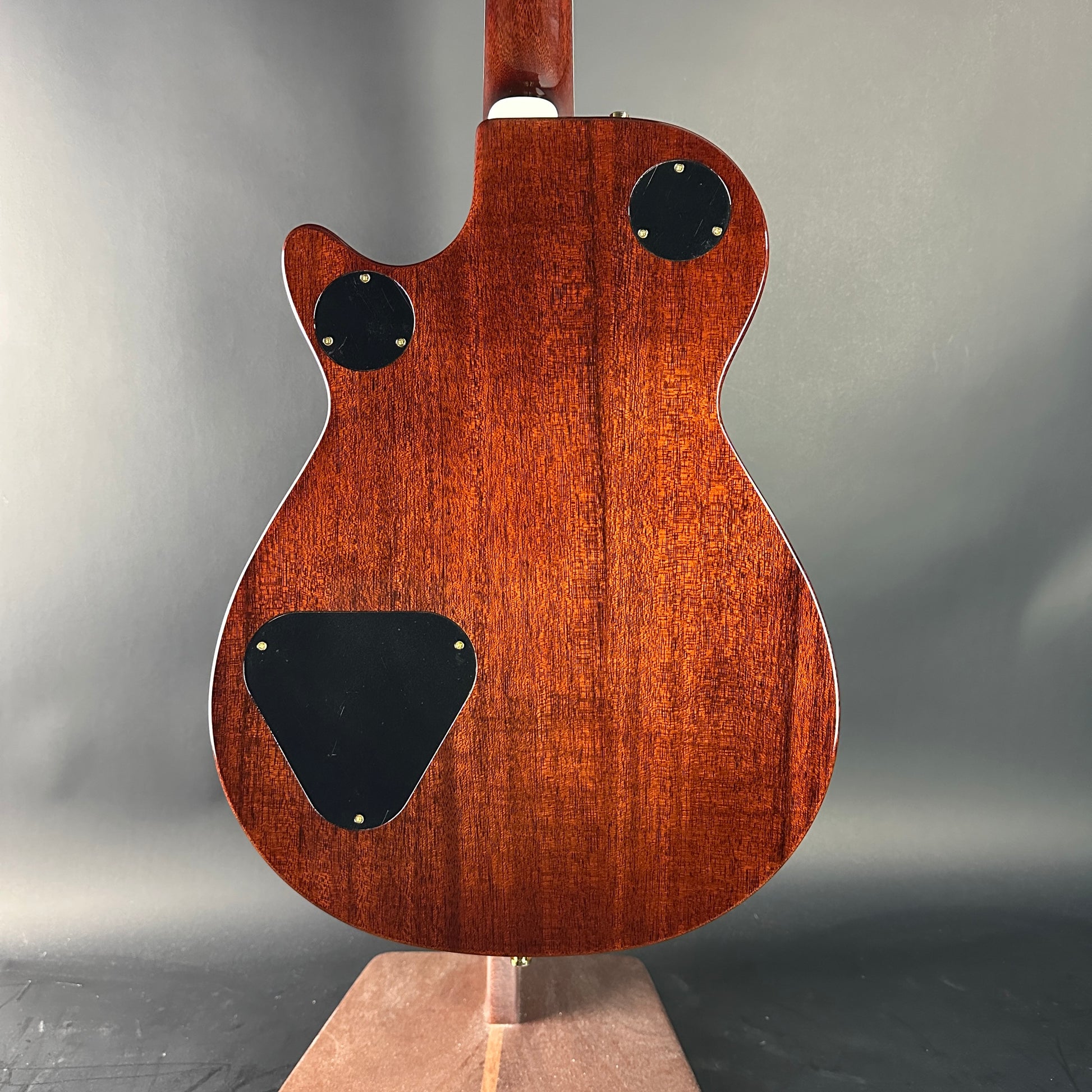 Back view of a wooden electric guitar on a gray background