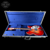 A red and orange sunburst electric guitar inside an open silver hard case with a blue velvet interior, shown against a black background. A 'TONE SHOP' watermark is visible in the top left corner.