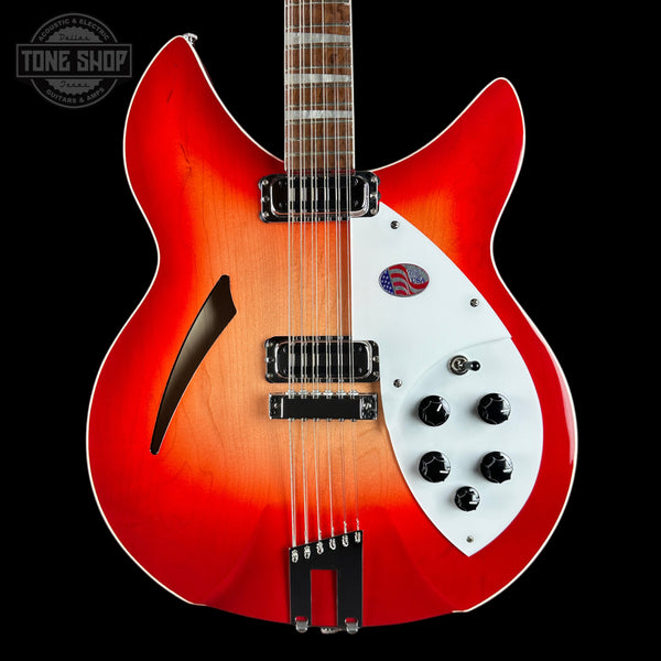 A double-cutaway electric guitar with a vibrant red-to-orange sunburst finish, a white pickguard, and black hardware, shown against a solid black background with a Tone Shop watermark in the top-left corner.