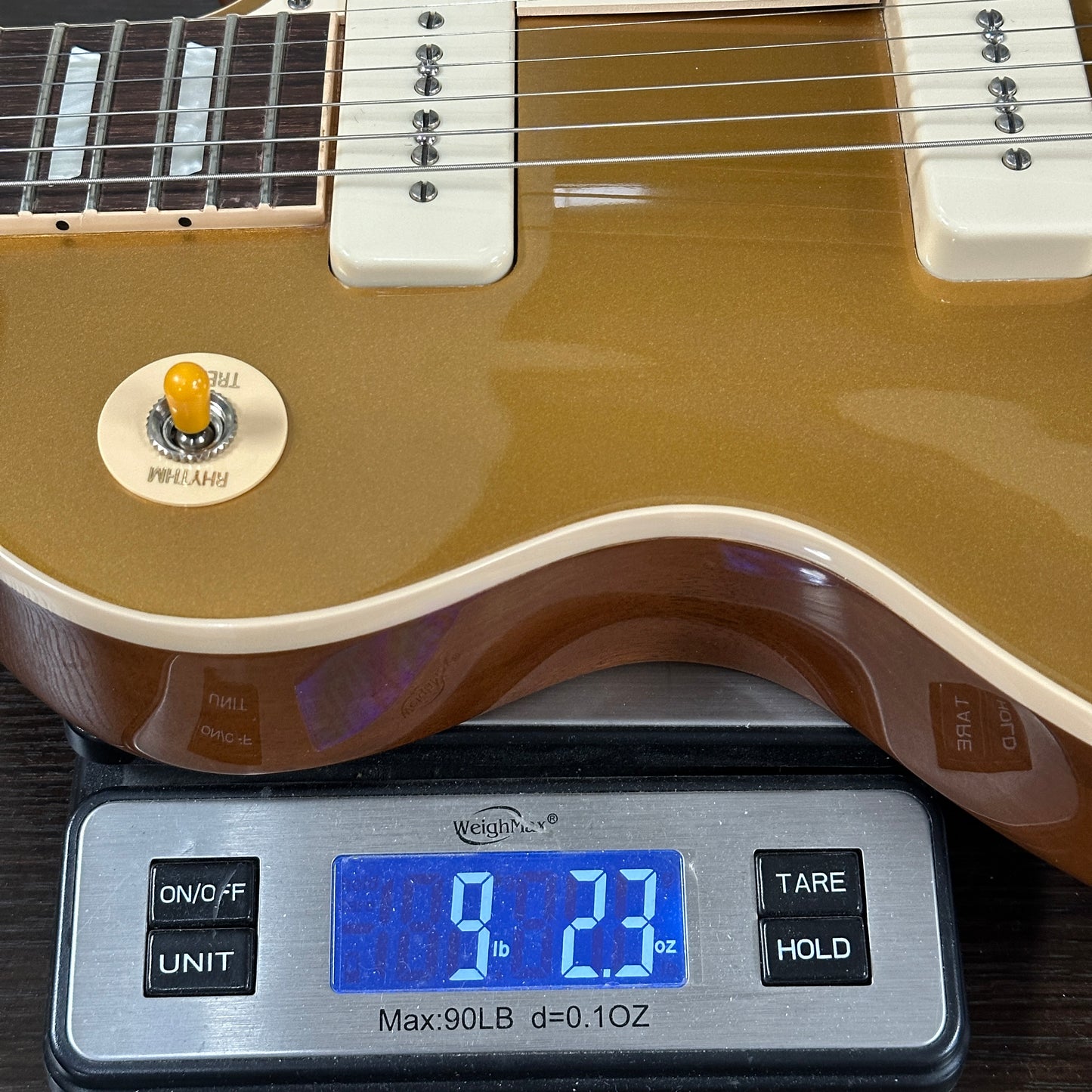 Gold electric guitar on a digital scale displaying weight