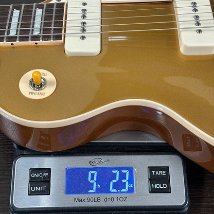 Gold electric guitar on a digital scale displaying weight