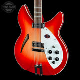 A double-cutaway electric guitar with a vibrant red-to-orange sunburst finish, a white pickguard, and chrome hardware, shown against a solid black background with a Tone Shop watermark in the top left corner.