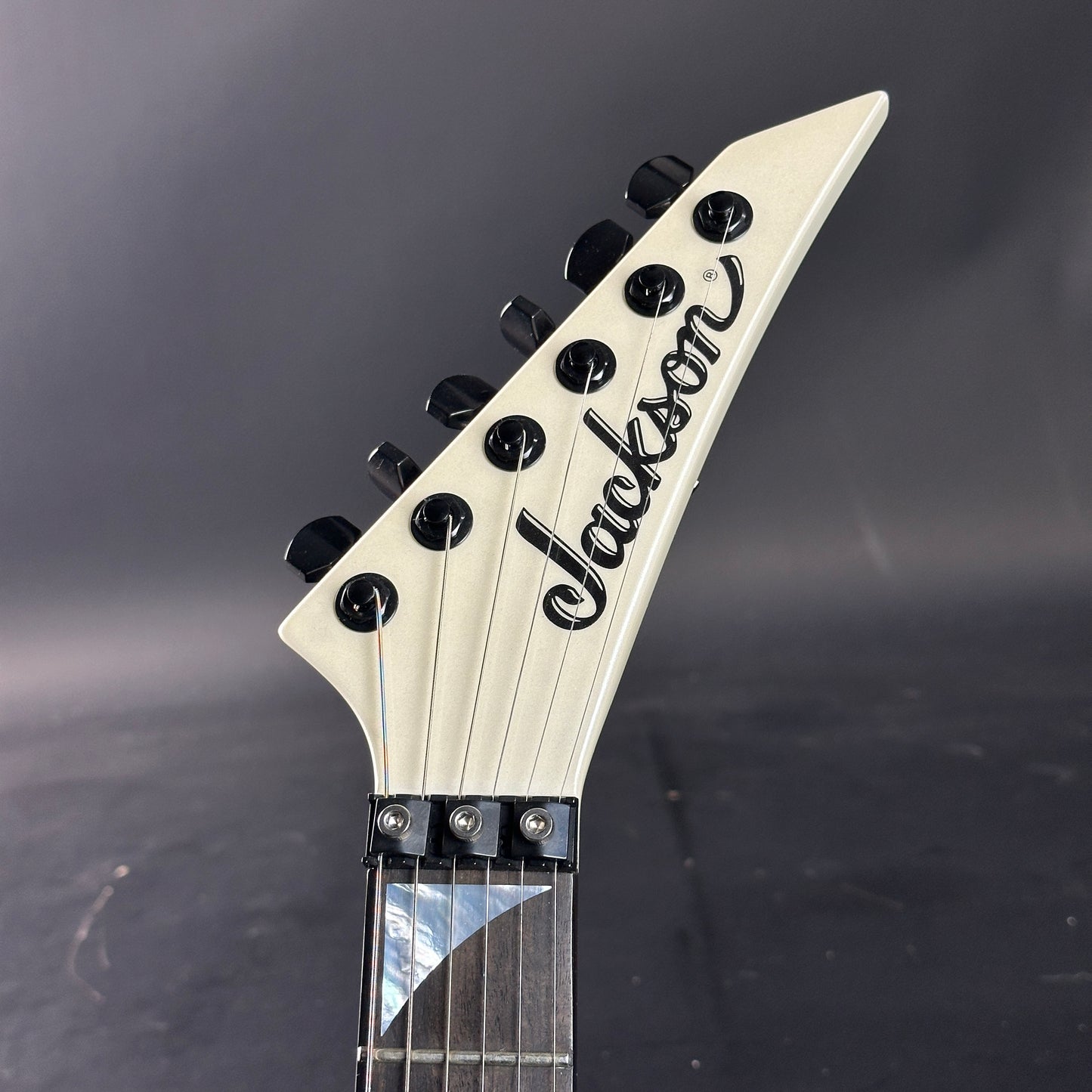 Close-up of a Jackson guitar headstock on a dark background