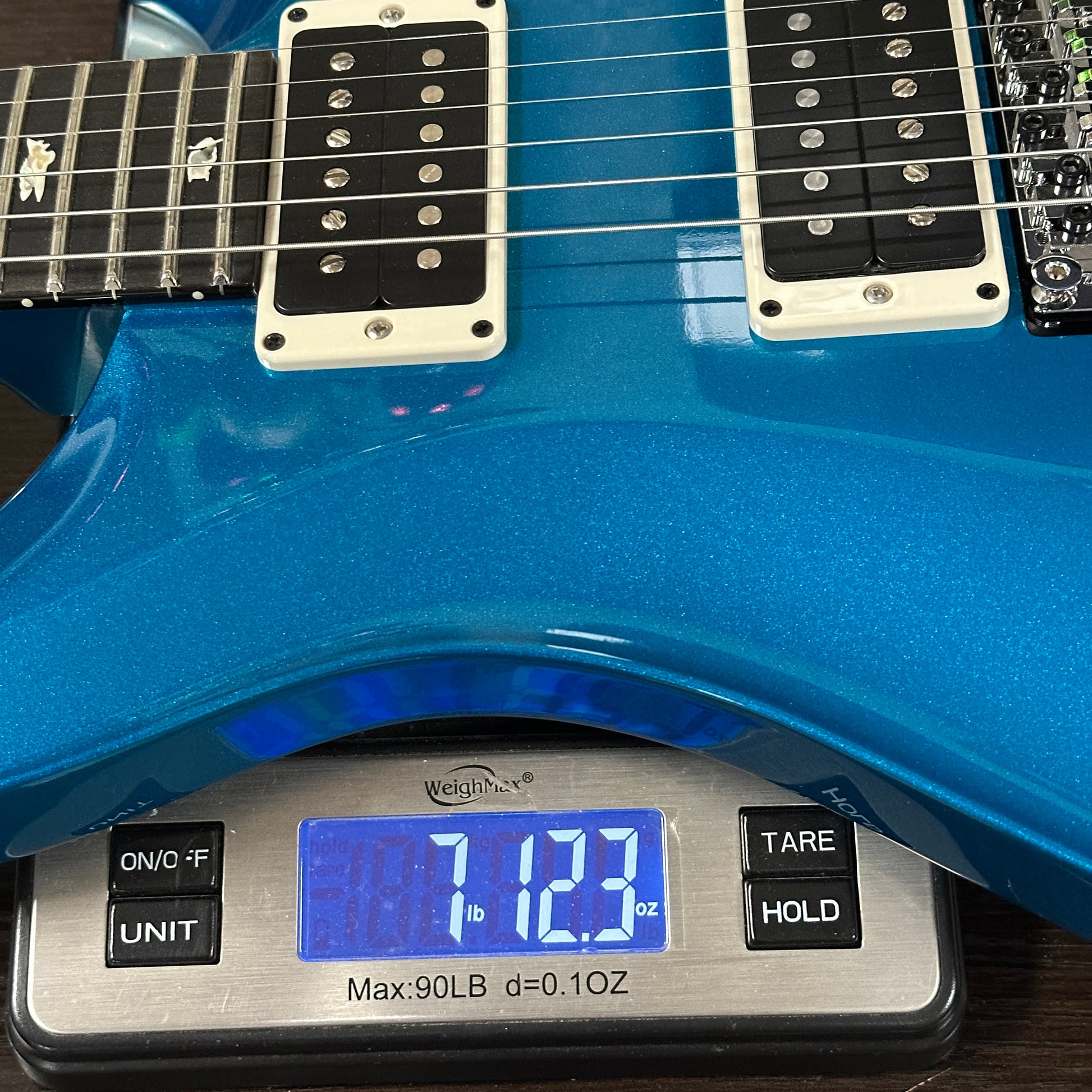 Blue electric guitar on a digital scale displaying weight