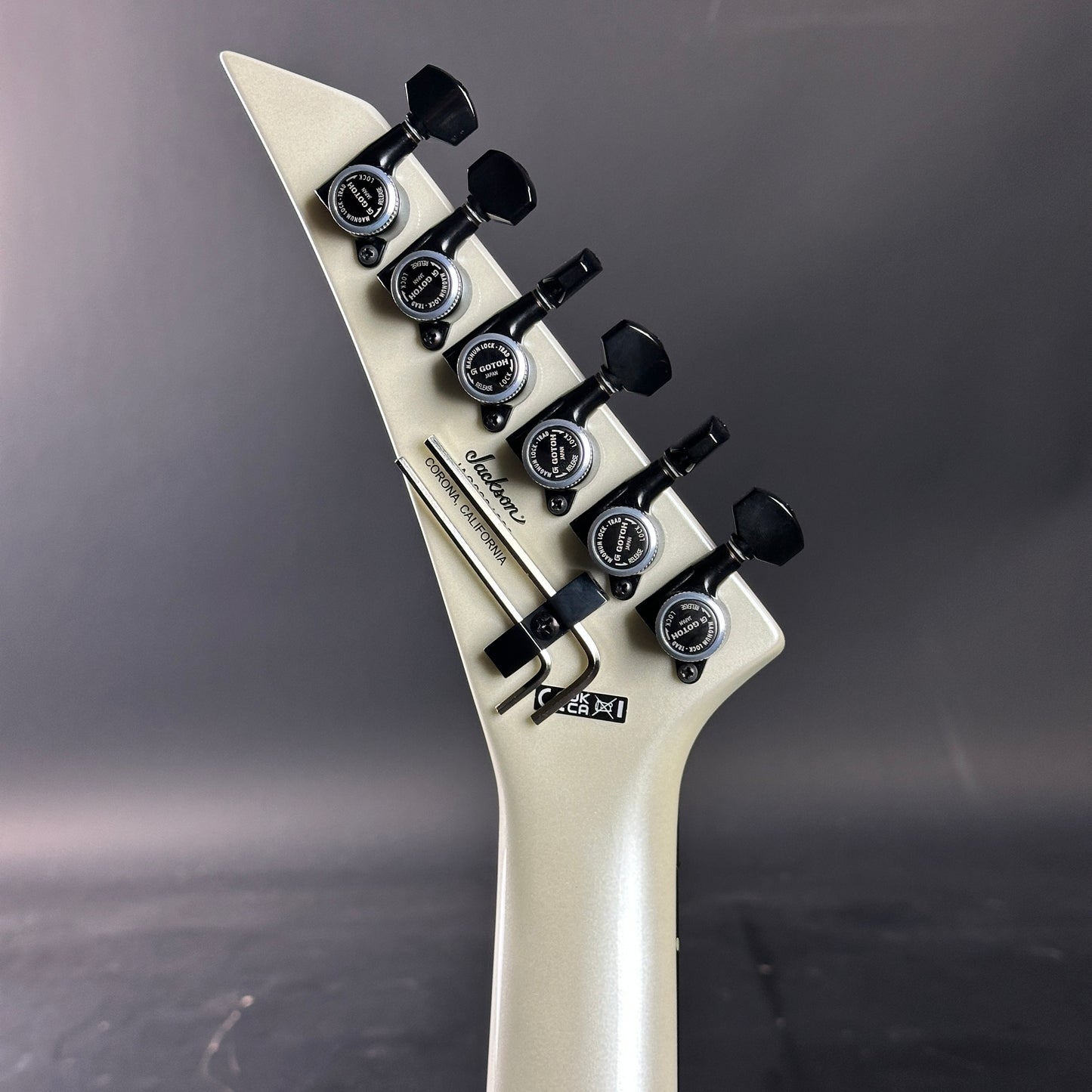 Guitar headstock with tuning pegs on a gray background