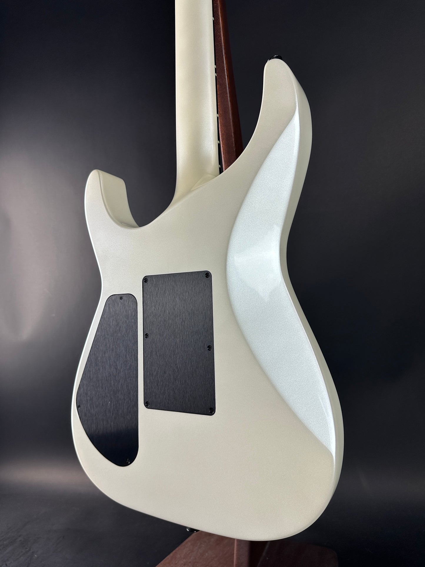 Close-up of a white electric guitar body on a dark background