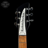 Close-up of the headstock of a Ricken-Rocker electric guitar against a black background, showing the brand name, tuning pegs, and part of the wooden fretboard.