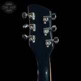 Close-up of the headstock of a black electric guitar against a black background, showing six silver tuning pegs with circular 'R' logos and a Tone Shop watermark in the upper left corner.