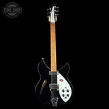 A black electric guitar with a white pickguard, maple neck, and chrome hardware, photographed against a solid black background. A Tone Shop watermark is visible in the top-left corner.