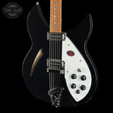 A black electric guitar with a white pickguard, maple neck, and chrome hardware, shown against a solid black background with a Tone Shop watermark in the top left corner.
