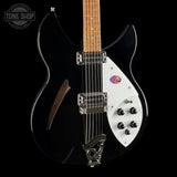 A black electric guitar with a white pickguard, chrome hardware, and a maple neck, shown against a black background with a Tone Shop watermark in the top left corner.