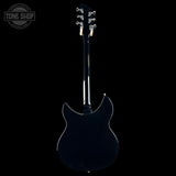 A glossy black electric guitar shown from the back, featuring a cutaway body, dark neck, and silver tuning pegs, set against a solid black background with a Tone Shop watermark in the top-left corner.