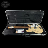 A double-cutaway electric guitar in a natural wood finish with a white pickguard, displayed inside an open silver hard case on a black background. The Tone Shop logo is visible in the top left corner.