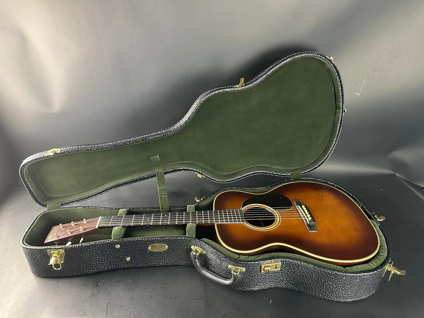 Acoustic guitar in a green case on a gray background