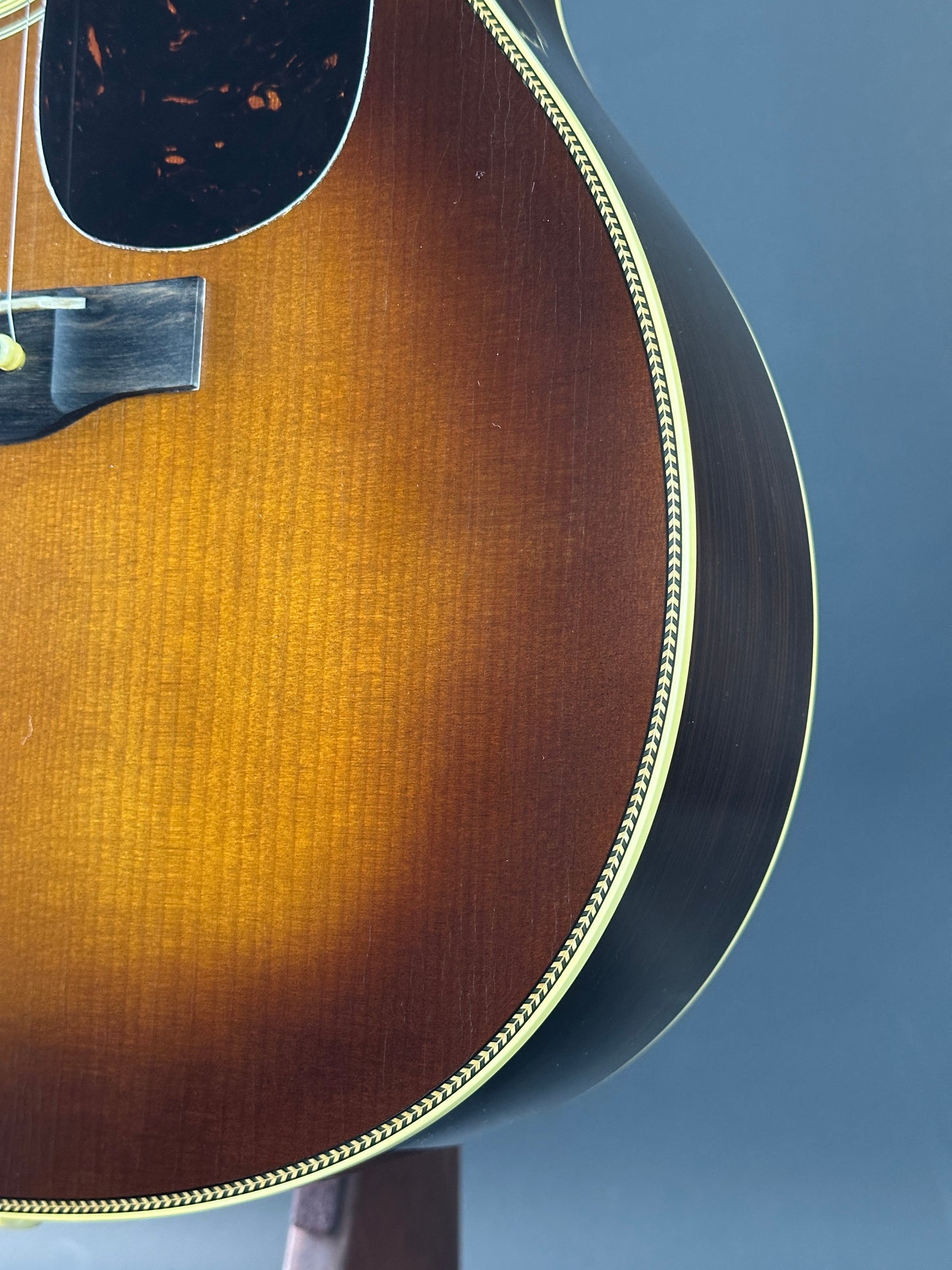 Close-up of a brown acoustic guitar with a blue background