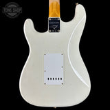 Back of a white electric guitar with Fender logo on a black background