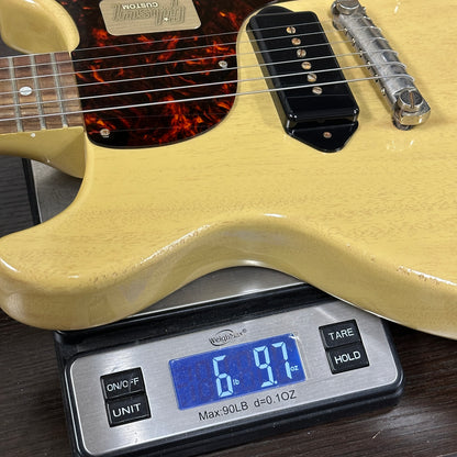 Beige electric guitar on a digital scale displaying weight
