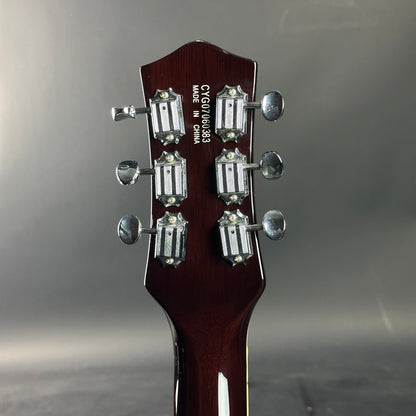 Guitar headstock with tuning pegs on a gray background
