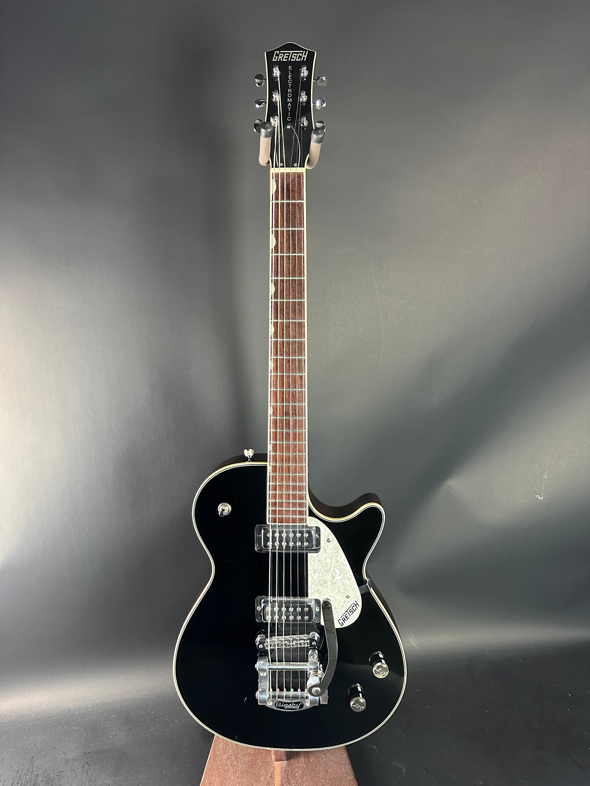 Black electric guitar on a reflective gray surface
