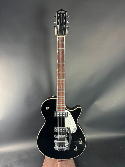 Black electric guitar on a reflective gray surface