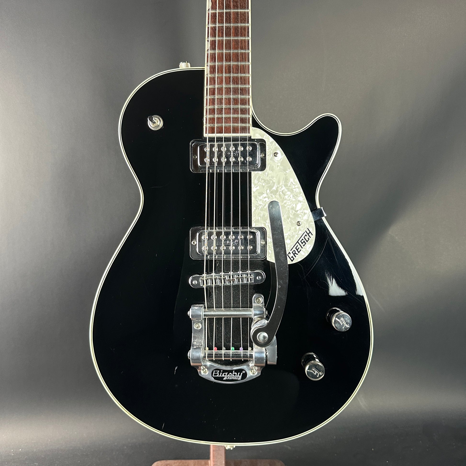 Black electric guitar on a gray background