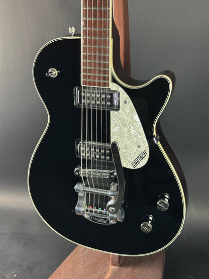 Black electric guitar with a visible brand logo on a dark background